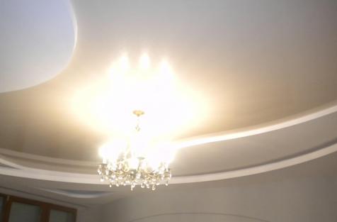 глянцевый натяжной потолок в гостиной с люстрой